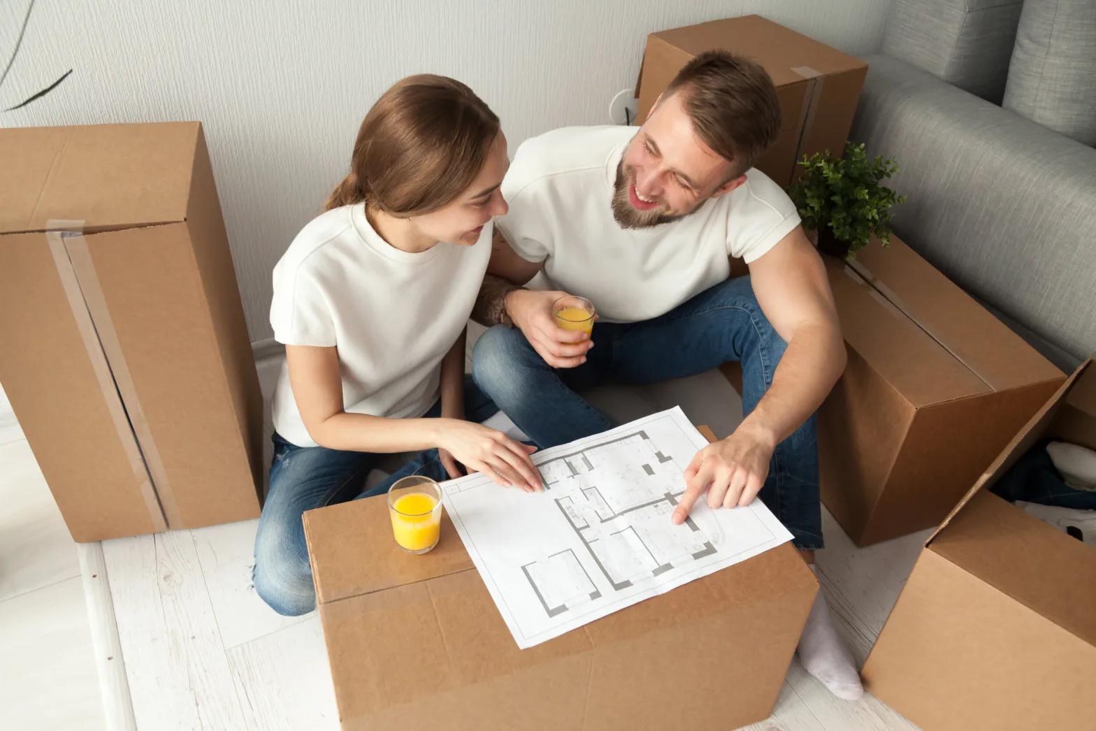 couple discussing house plan sitting on floor with moving boxes