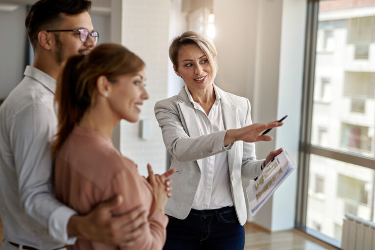 Blog 1 agente inmobiliario sonriente hablando con una pareja interesada en comprar una casa nueva
